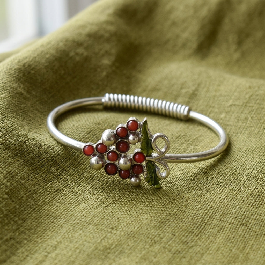 Silver tone vineyard wine grapes bracelet resting on green linen