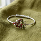 Silver tone vineyard wine grapes bracelet resting on green linen
