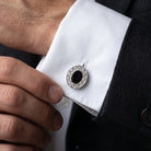 Close-up of a black stone cufflink on a white shirt.
