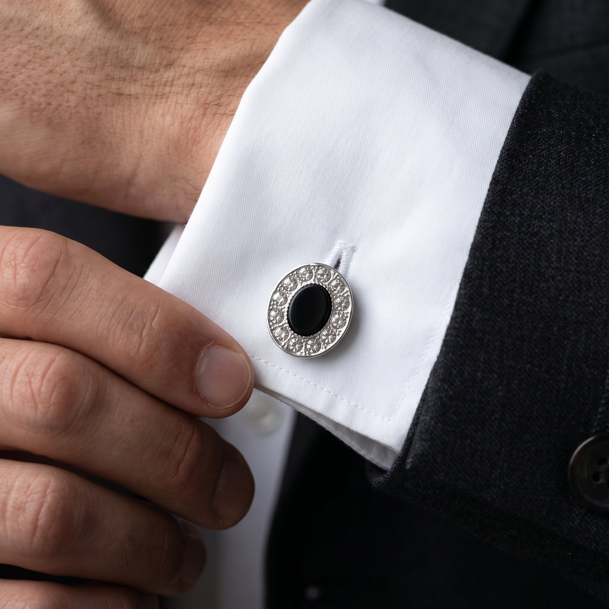 Close-up of a black stone cufflink on a white shirt.