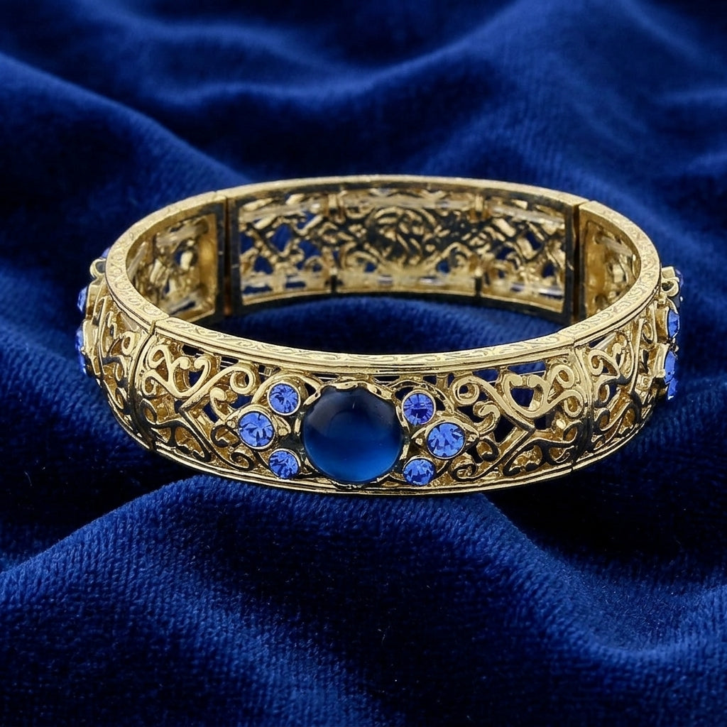 Gold Tone Blue Genuine Mother Of Pearl Crystal Accent Stretch Bracelet on a blue fabric background