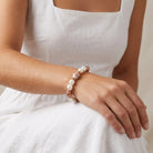 Woman in a white dress wearing a Rose Faux Pearl Purple Flower Filigree Beaded Stretch Bracelet