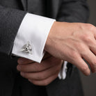 Silver Cufflink with airplane propeller design on a white cuff against a dark suit background