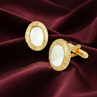 Gold cufflinks with white stones on a burgundy fabric background