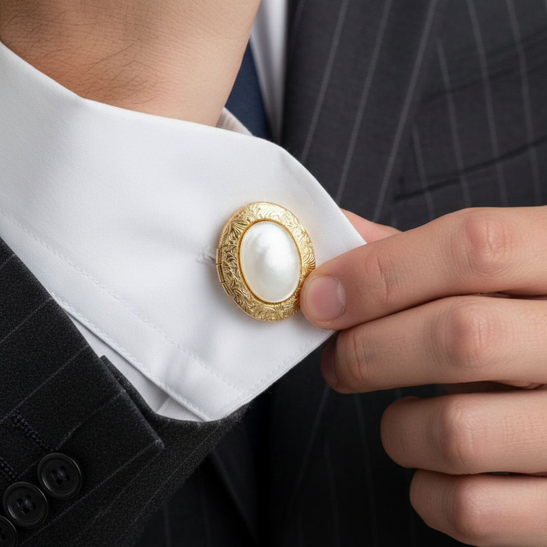 Gold cufflink with a white, semi-precious gemstone on a white shirt cuff. 