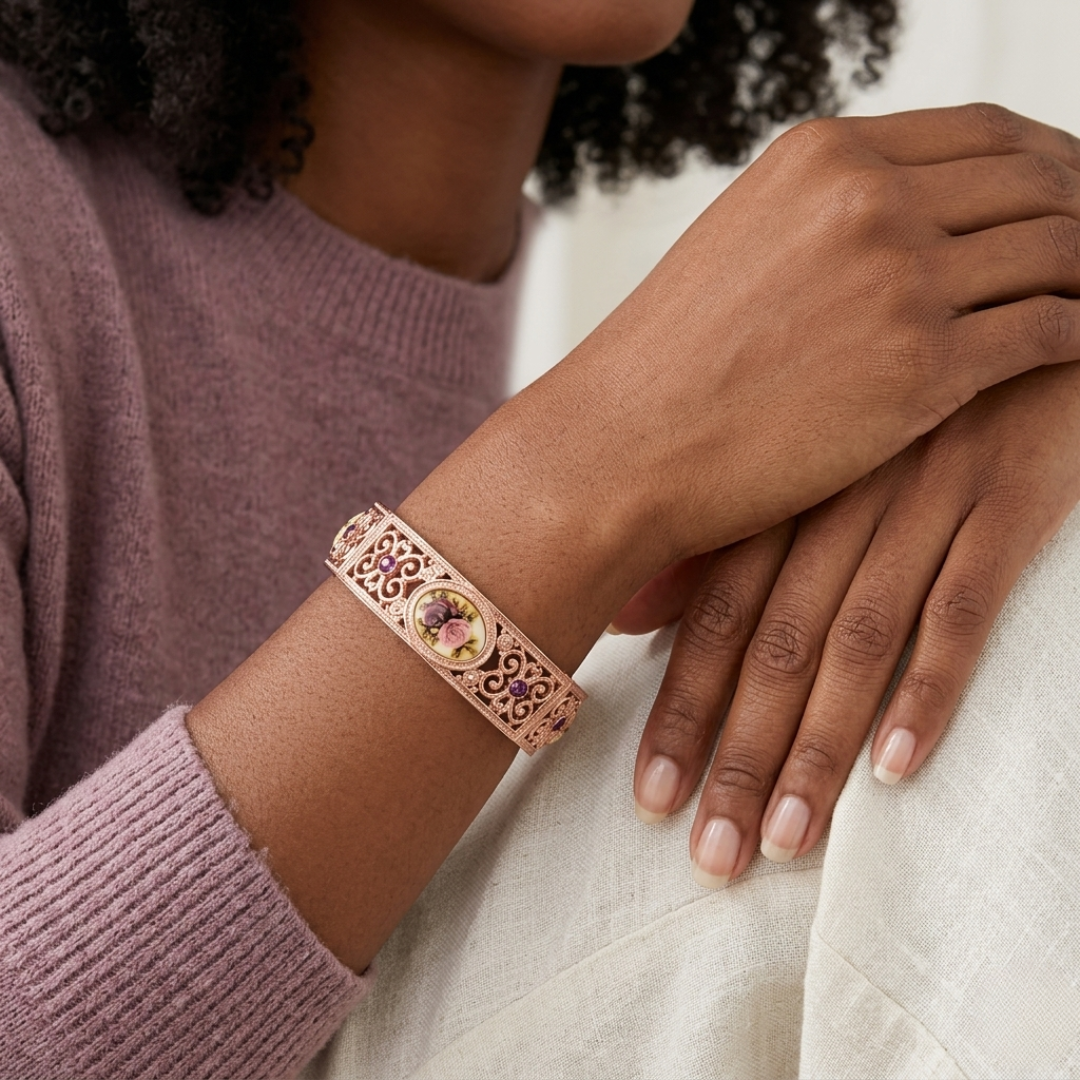 Person wearing a decorative rose gold floral bracelet with purple crystals on a neutral background