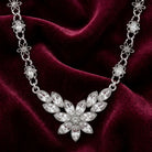 Silver crystal necklace with a floral design on a burgundy fabric background
