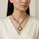 Woman wearing a detailed pewter chain necklace with clear crystals with a cream top