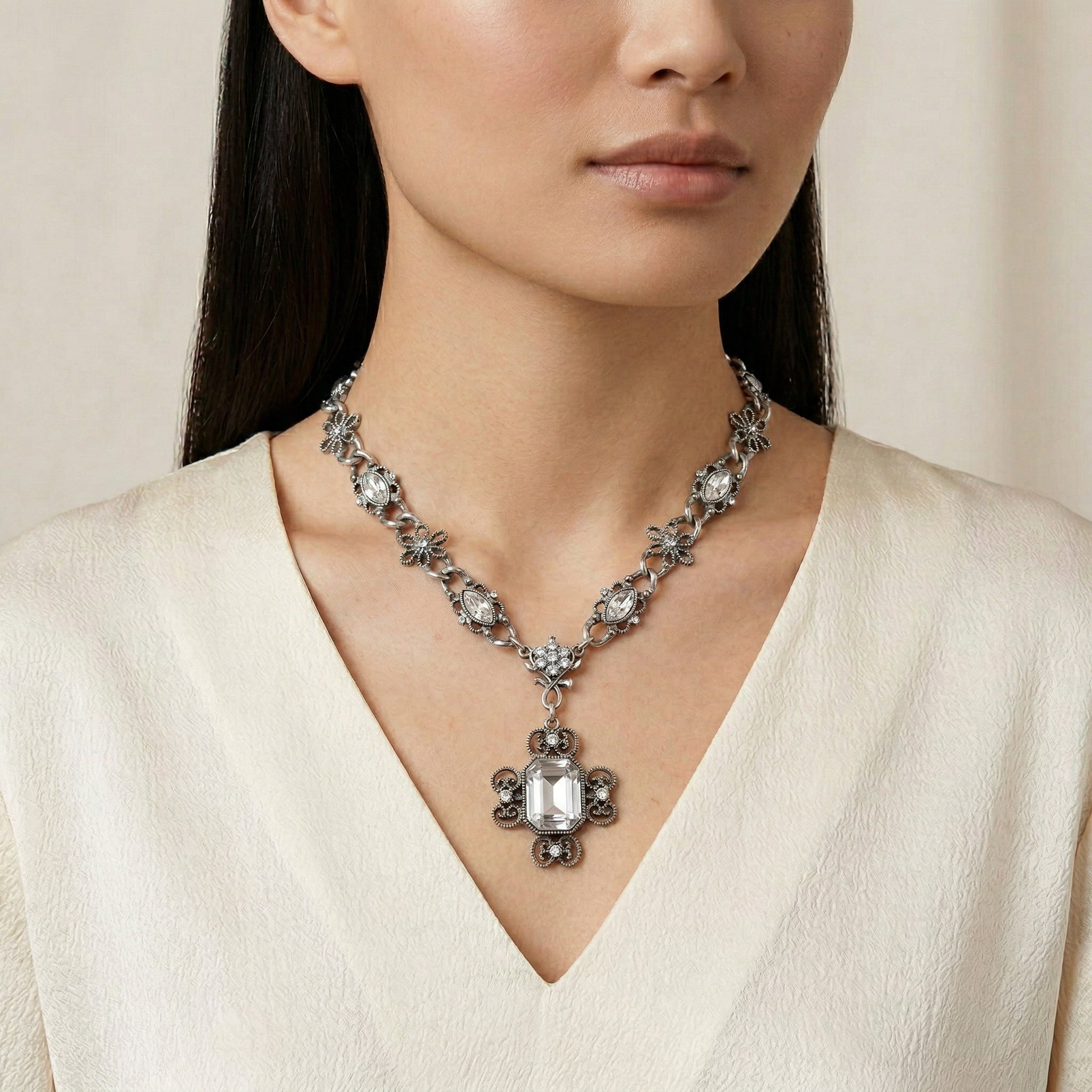Woman wearing a detailed pewter chain necklace with clear crystals with a cream top
