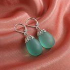 Aquamarine egg-shaped earrings with silver leverbackings on pink satin