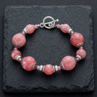 Roseate Paradise Oval Coral Quartz Stone & Pink Crystals Toggle Bracelet on black stone