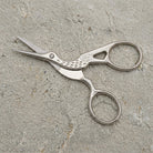 Crane Bird Designed Scissors With Pouch on a textured stone surface