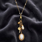 Elegant gold tone Faux Pearl Locket With Whistle Bell Charm Necklace on dark fabric