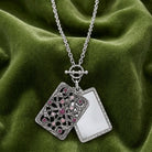 Opened silver tone Purple Amethyst Crystal Filigree Mirror Pendant Necklace on green fabric