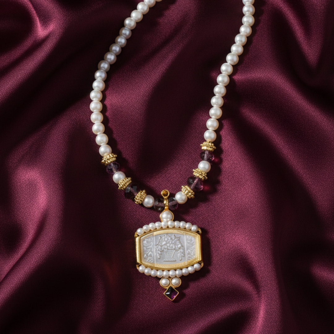 Faux pearl necklace with a decorative flower bouquet pendant on a burgundy fabric background