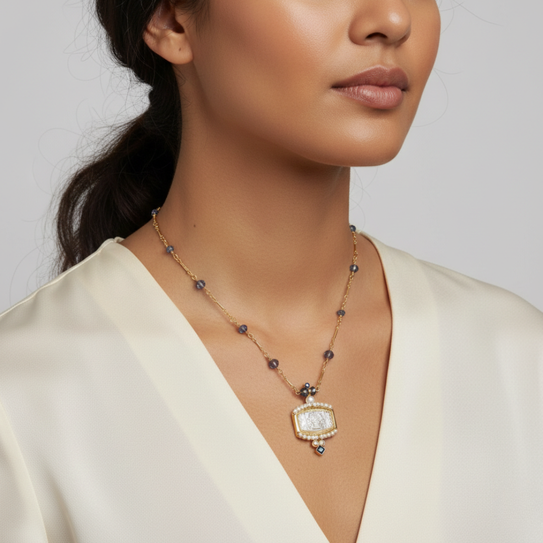 Woman wearing a gold necklace with blue beads and a floral bouquet pendant against a neutral background
