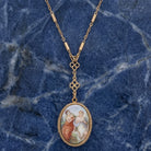 Gold tone Pre-Raphaelite Art Inspired Locket Necklace resting on blue marble stone