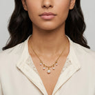 Gold tone Cinque White Faux Pearl Drop Necklace worn by a woman in a white top.