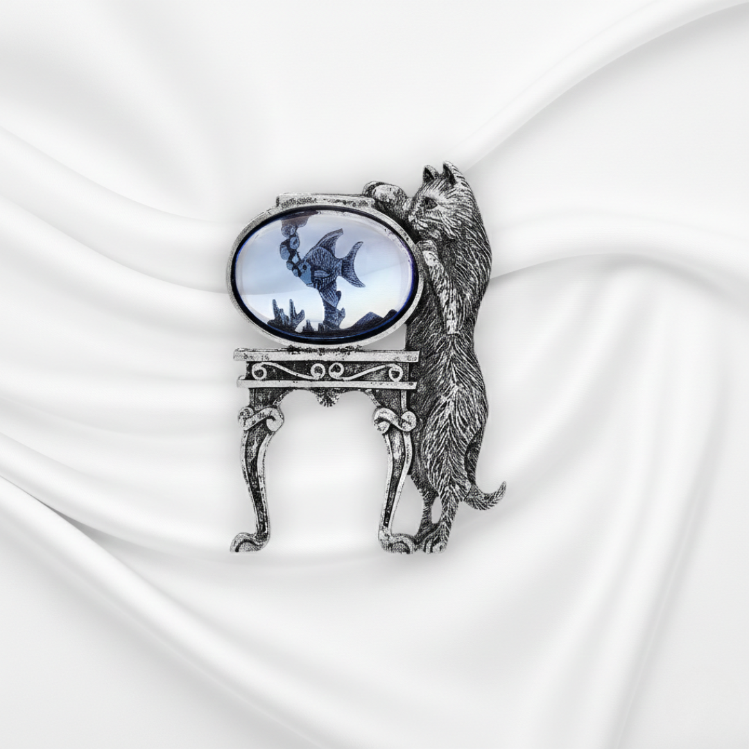 Decorative brooch with a cat design on a white fabric background.