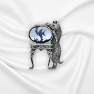 Decorative brooch with a cat design on a white fabric background.