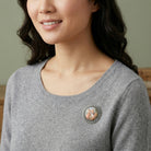 Silver tone Round Rubenesque Glass Decal Brooch worn by a woman with a gray sweater