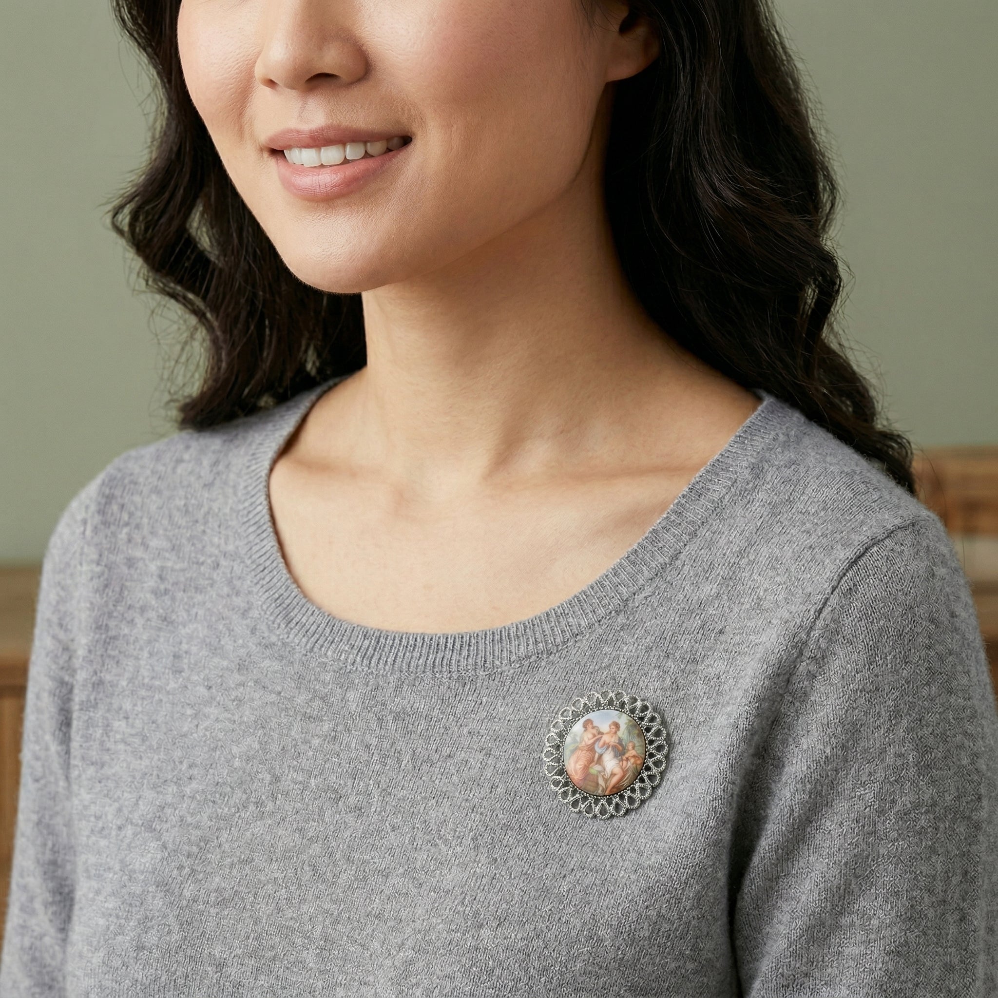 Silver tone Round Rubenesque Glass Decal Brooch worn by a woman with a gray sweater