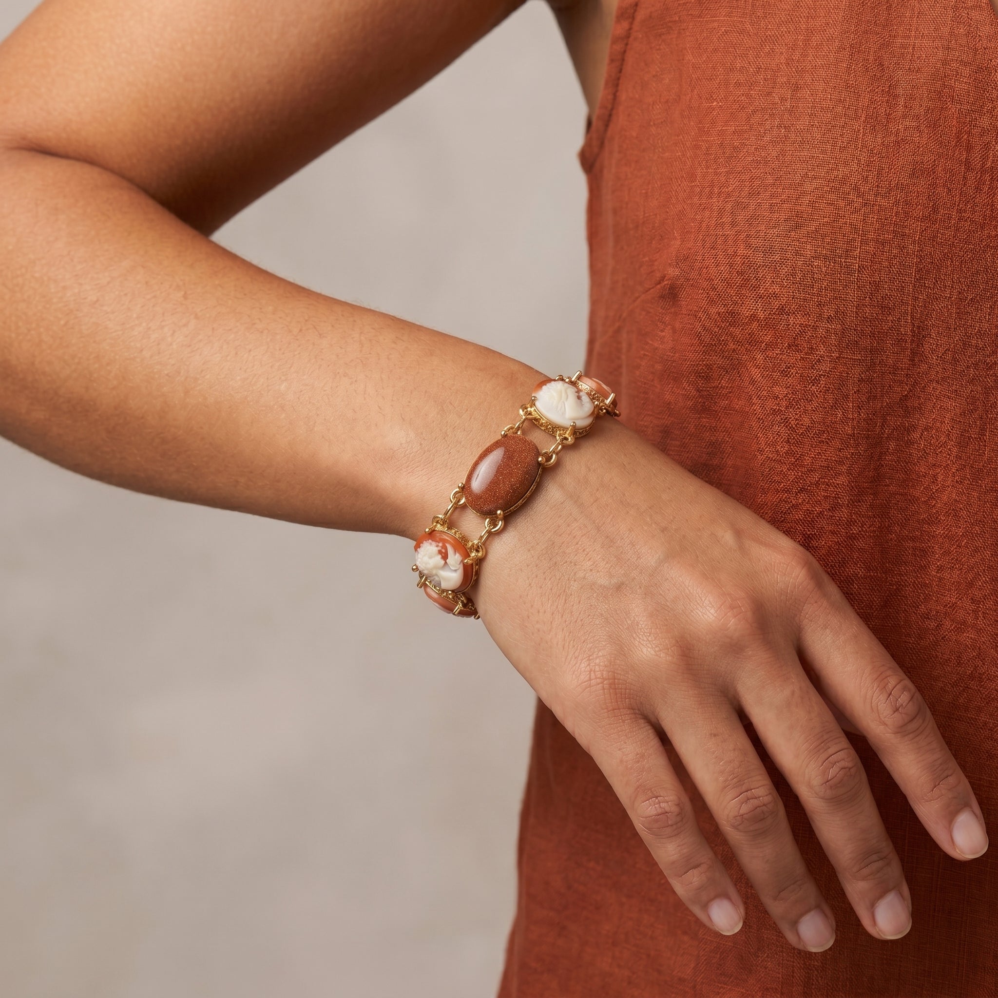 Person wearing a gold tone Oval Cameo & Goldstone Gemstone Link Bracelet