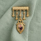 Gold tone Manor House Royal Rose & Charms Bar Pin on light green linen