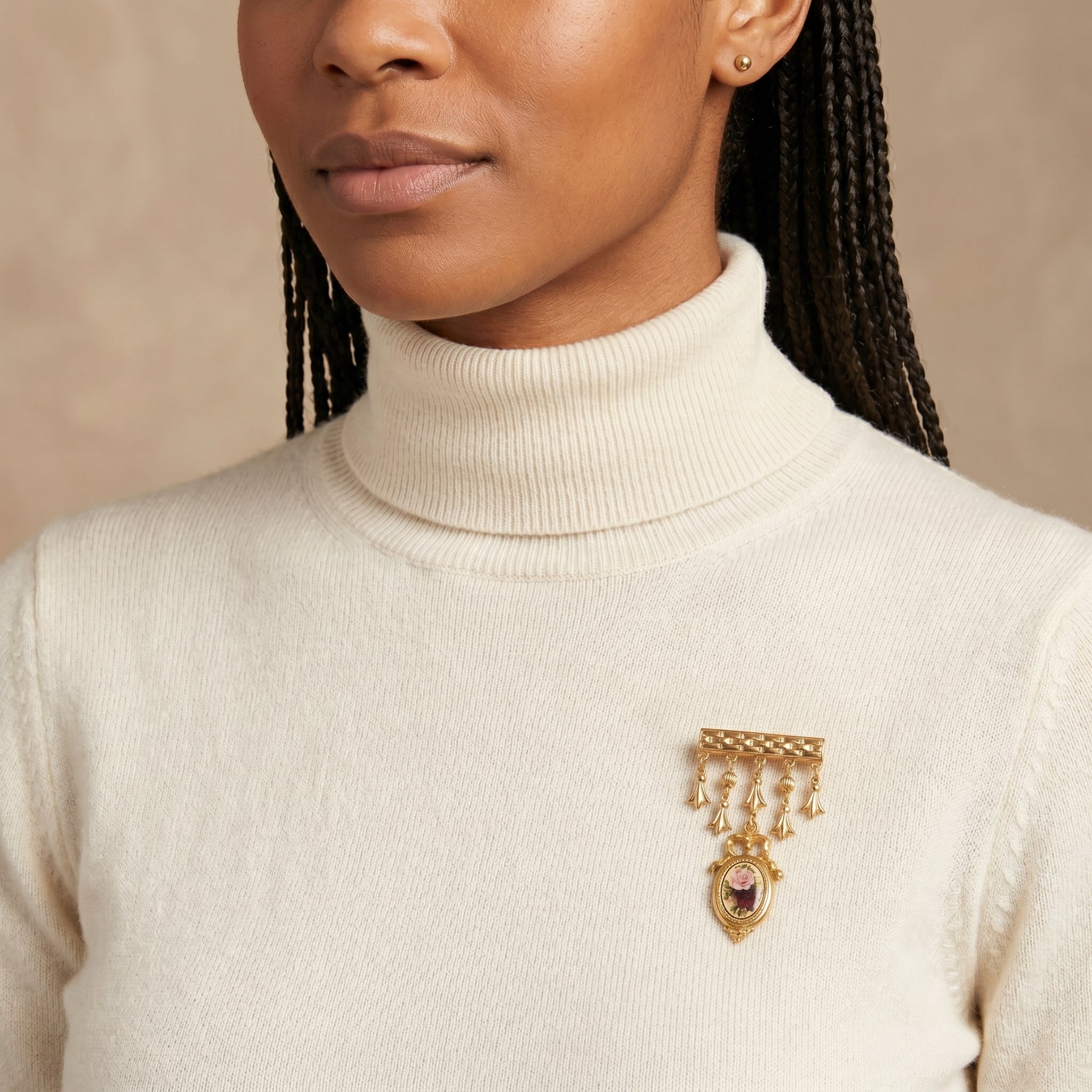 Woman wearing a gold tone Manor House Royal Rose & Charms Bar Pin brooch on a beige sweater against a neutral background