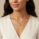 Woman in a white top wearing a gold tone Love Initials Heart Pendant Necklace