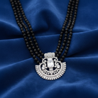 Black beaded necklace with a silver pendant on a blue fabric background