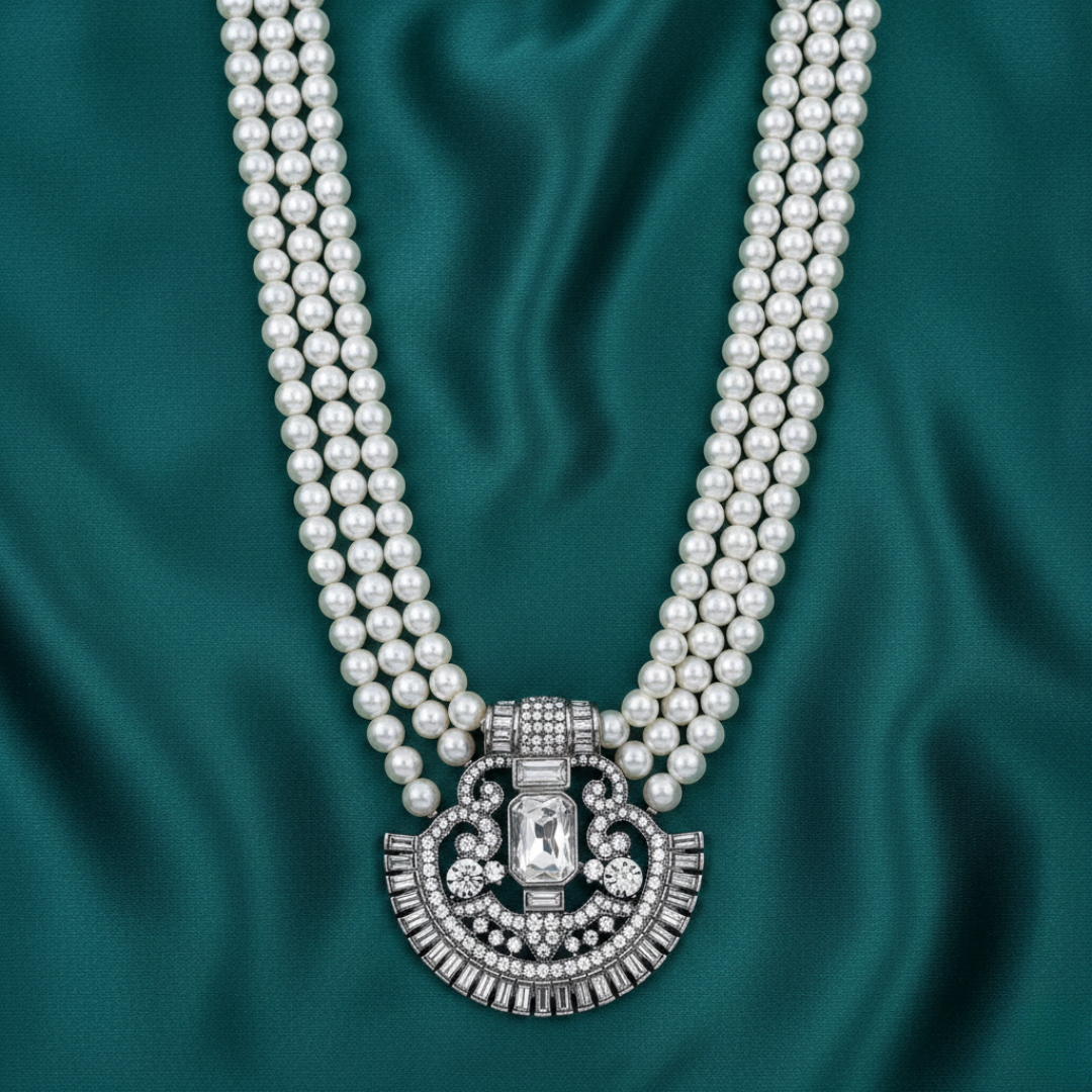 Pearl necklace with a silver clasp on a teal fabric background