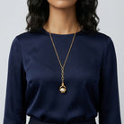 Person wearing a navy blue top and a gold tone 3-Sided Pink Floral Spinner Drop Locket Necklace 