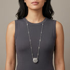 Vintage Silver Tone Purse Pendant Necklace worn by a woman in a long dark gray sleeveless top