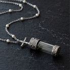 Faux Pearl Pewter Cross Cap Vial Necklace on a dark stone surface