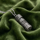 Etched Pewter Floral Glass Vial Necklace  lying on green fabric