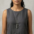 Etched Pewter Floral Glass Vial Necklace worn by a woman in a gray sleeveless top