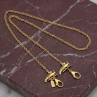 Gold tone Airplane Face Mask Chain Holder resting on muted red marble stone