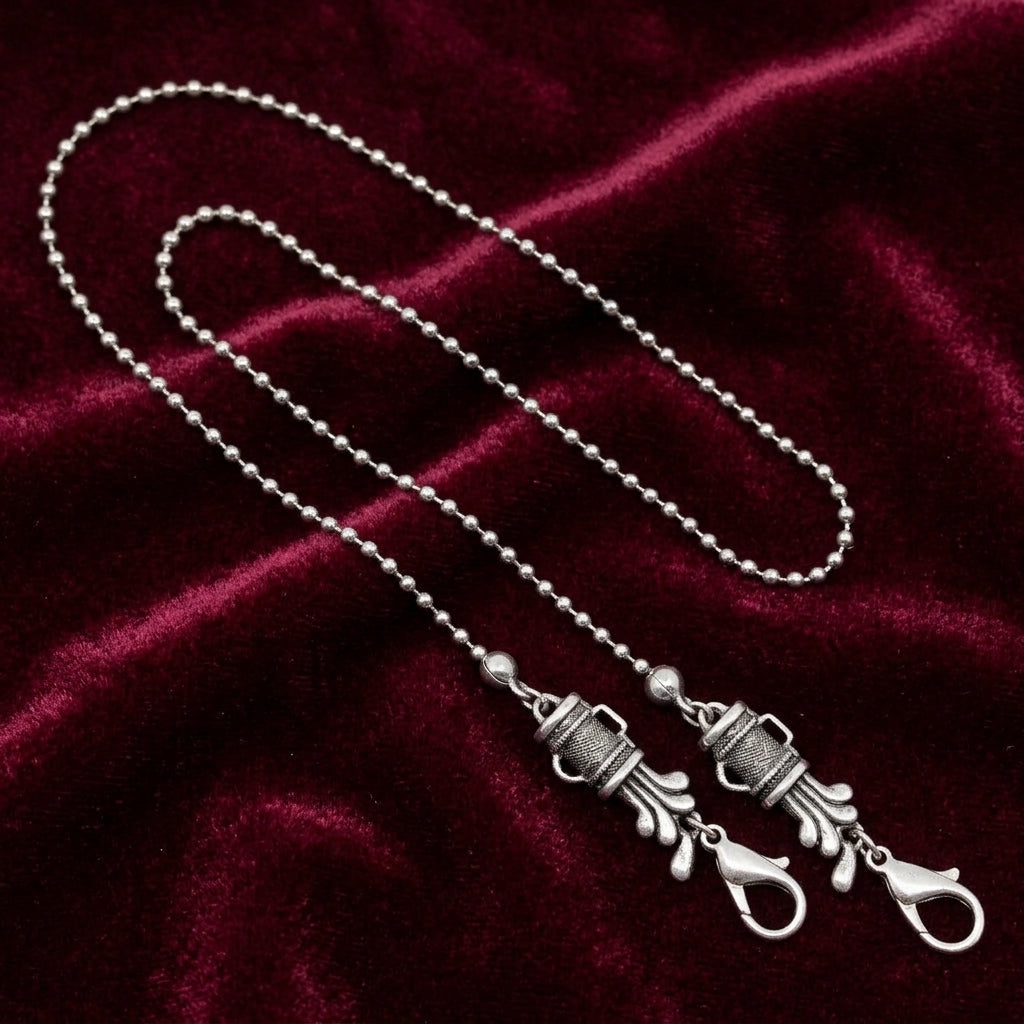 Silver tone golf club set mask chain holder resting on dark red fabric