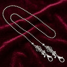 Silver tone golf club set mask chain holder resting on dark red fabric