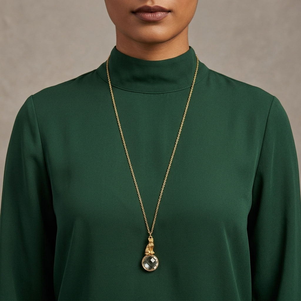 Person wearing a green turtleneck with a gold necklace featuring a topaz crystal pendant.