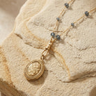 Blue Montana Glass Beaded Double Side Oval Floral Locket Necklace on a textured beige surface