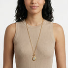 Woman wearing a beige ribbed tank top and a gold Oval Crystal Filigree Double Locket Necklace
