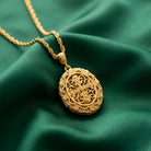 Gold necklace with a intricate locket pendant on a green fabric background