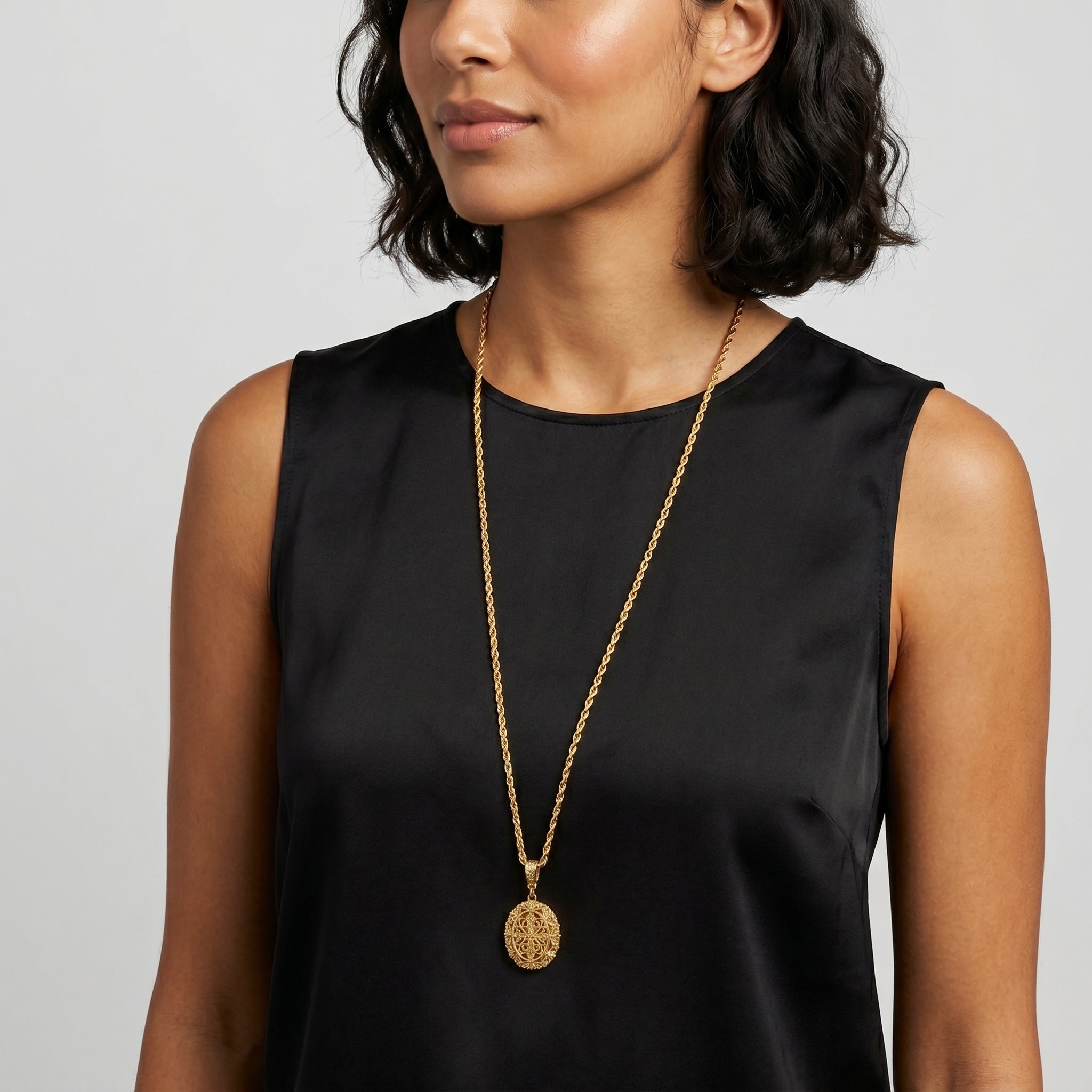 Woman wearing a black sleeveless top and a Oval Filigree Cross Double Sided Locket Necklace