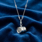 Vintage Spring Loaded Nickel Coin Holder Dispenser Pendant Necklace on a blue fabric background