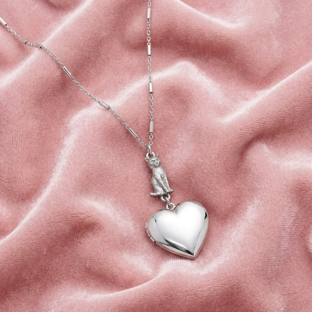 Sitting Cat And Heart Locket Necklace on a pink textured fabric background