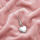 Sitting Cat And Heart Locket Necklace on a pink textured fabric background