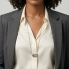 Person wearing a gray blazer and cream shirt with a Montana Blue Crystal Flower Purse Locket Necklace