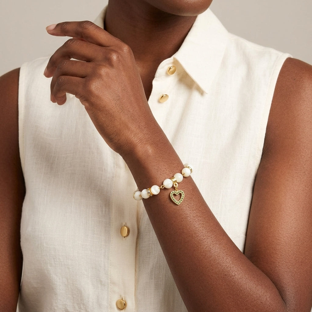 Woman in a white top wearing a Mother of Pearl Crystal Birthstone Heart Charm Bracelet on a neutral background